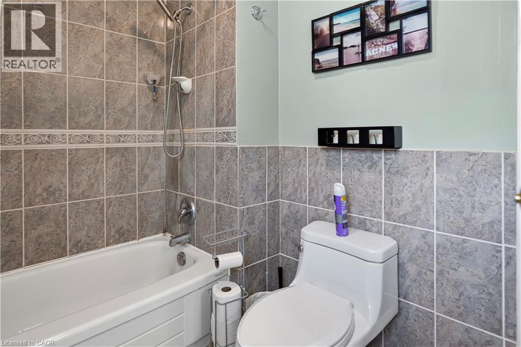 Bathtub with an integrated shower head and a tiled surround extending to the ceiling - 234 Thunderbird Drive, Cambridge, ON - Indoor Photo Showing Bathroom