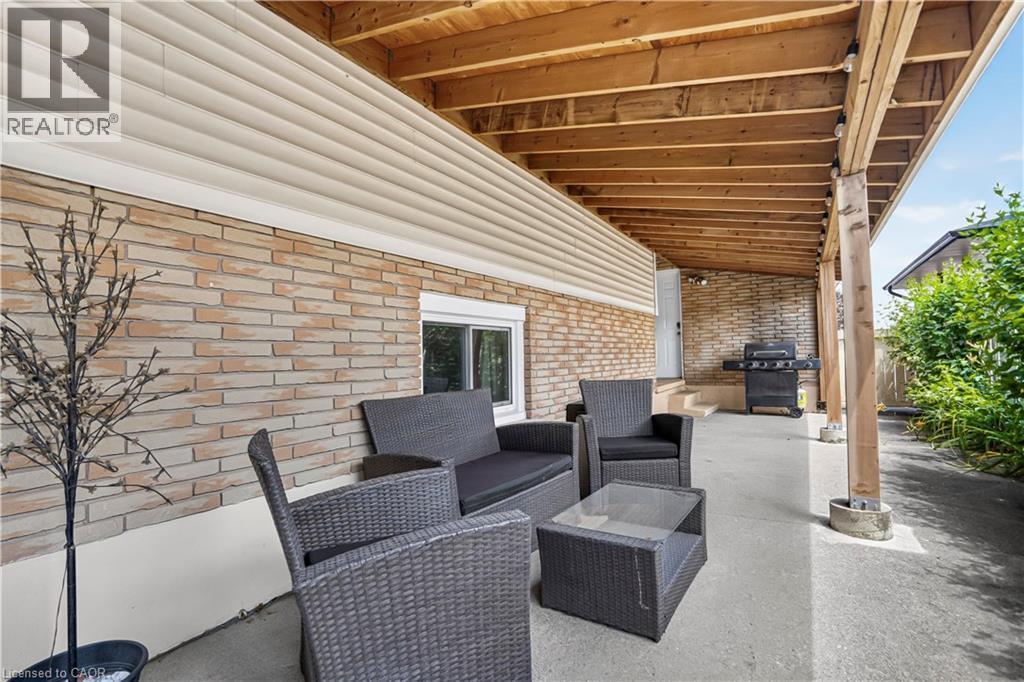 Spacious covered patio featuring a wood-beam ceiling, brick facade, and concrete flooring - 234 Thunderbird Drive, Cambridge, ON - Outdoor With Deck Patio Veranda With Exterior