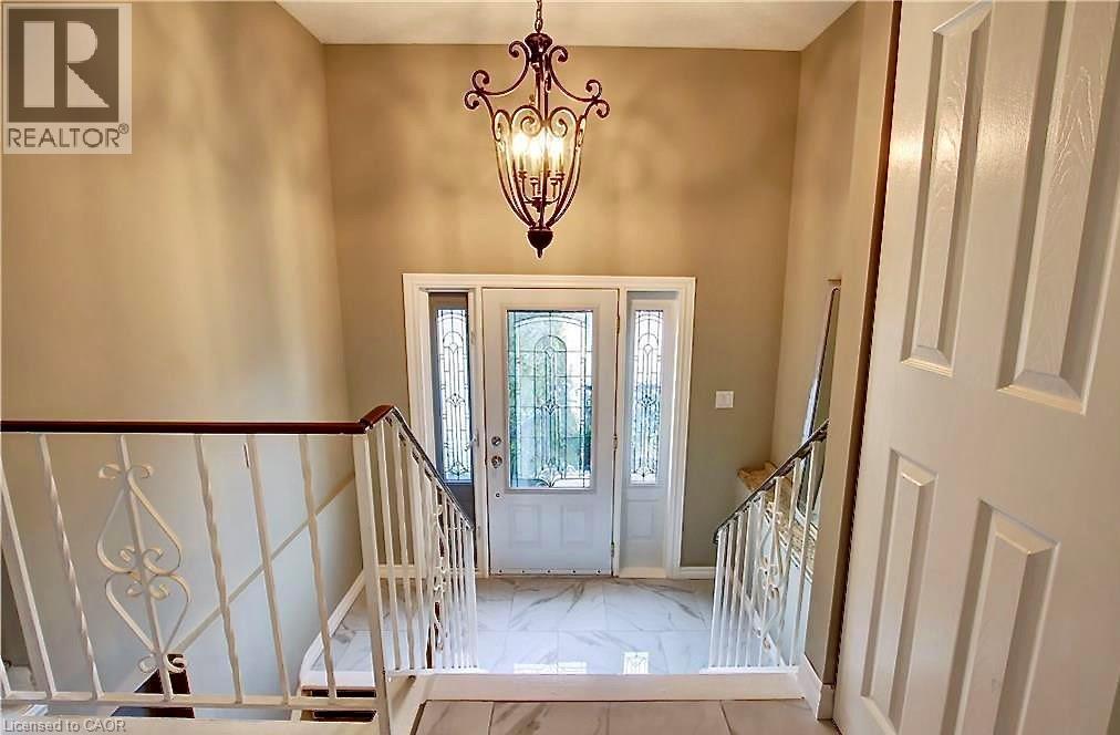 Foyer featuring a decorative wrought iron chandelier, white entry door with frosted glass panels, two sidelight windows, and marble-look tile flooring - 599 Upper Horning Road Unit# Main/Upper, Hamilton, ON