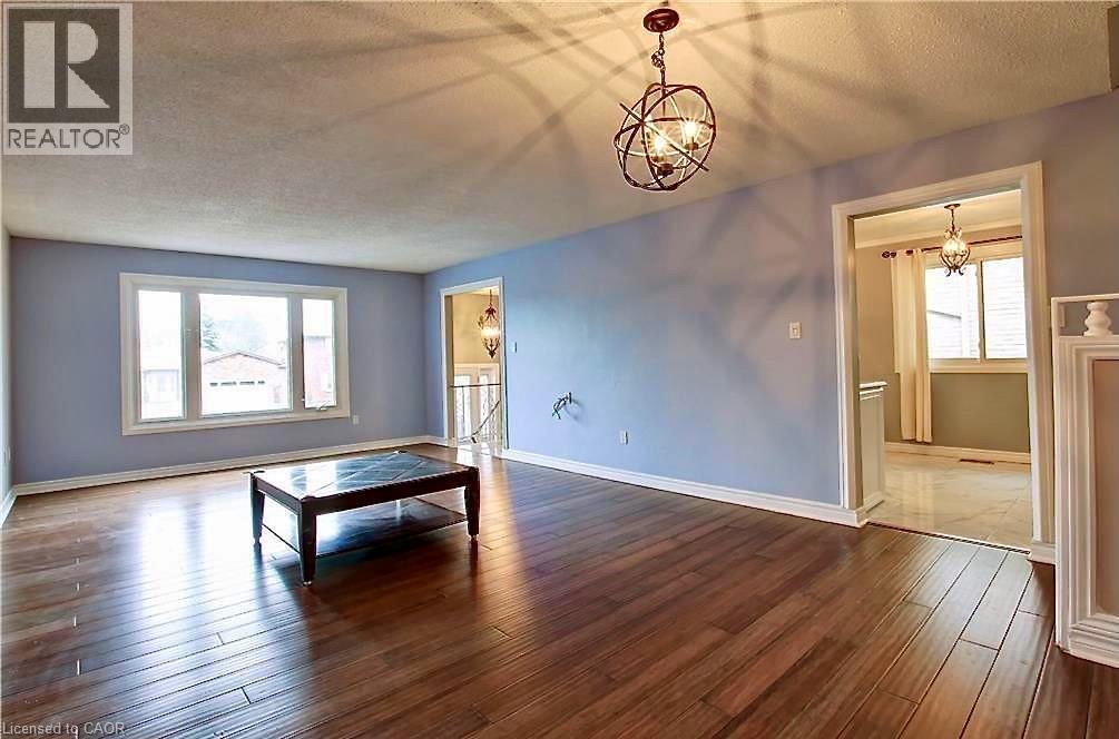 Spacious living area featuring wood-finish flooring, light blue walls, and white baseboards - 599 Upper Horning Road Unit# Main/Upper, Hamilton, ON