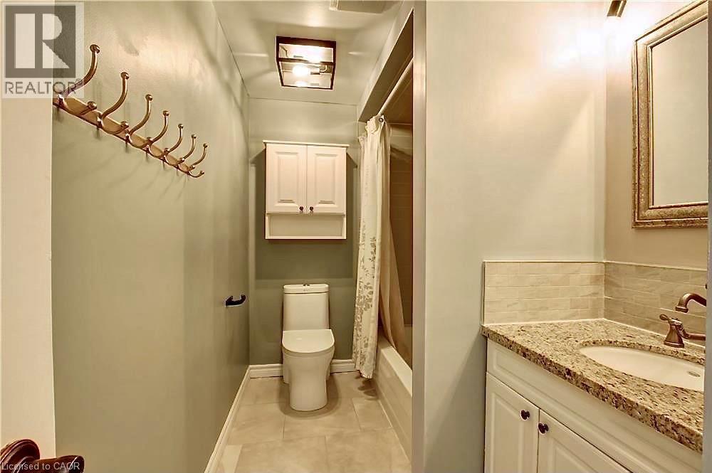Full bathroom featuring a white vanity with a granite-style countertop, an undermount sink, and a framed mirror - 599 Upper Horning Road Unit# Main/Upper, Hamilton, ON