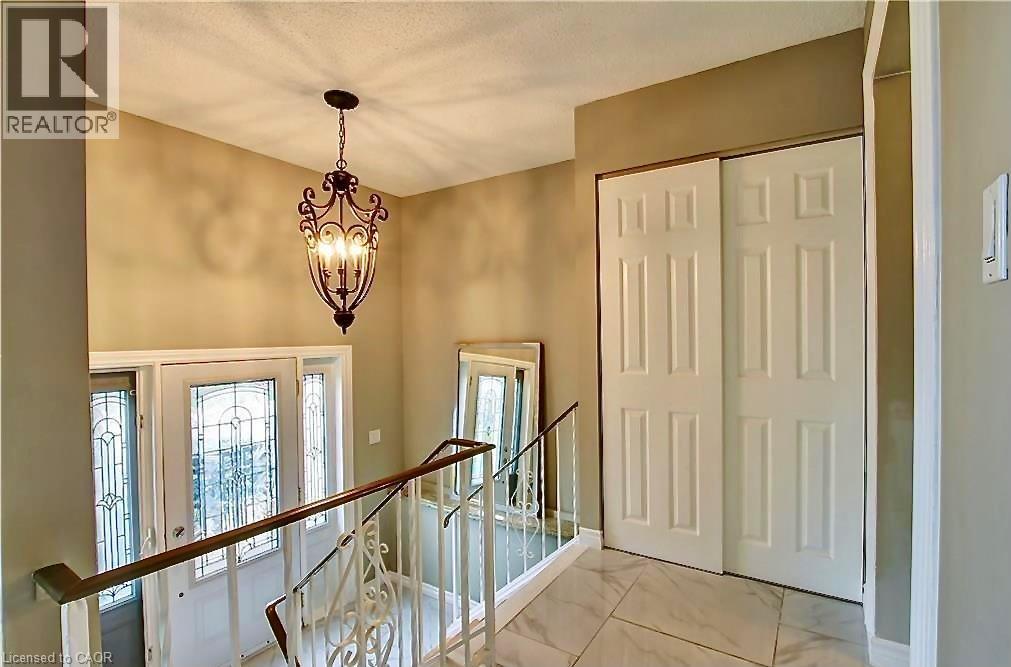 Foyer featuring an ornate chandelier, leaded glass front entry door with sidelights, a wood handrail with white spindles, and a bi-fold closet - 599 Upper Horning Road Unit# Main/Upper, Hamilton, ON