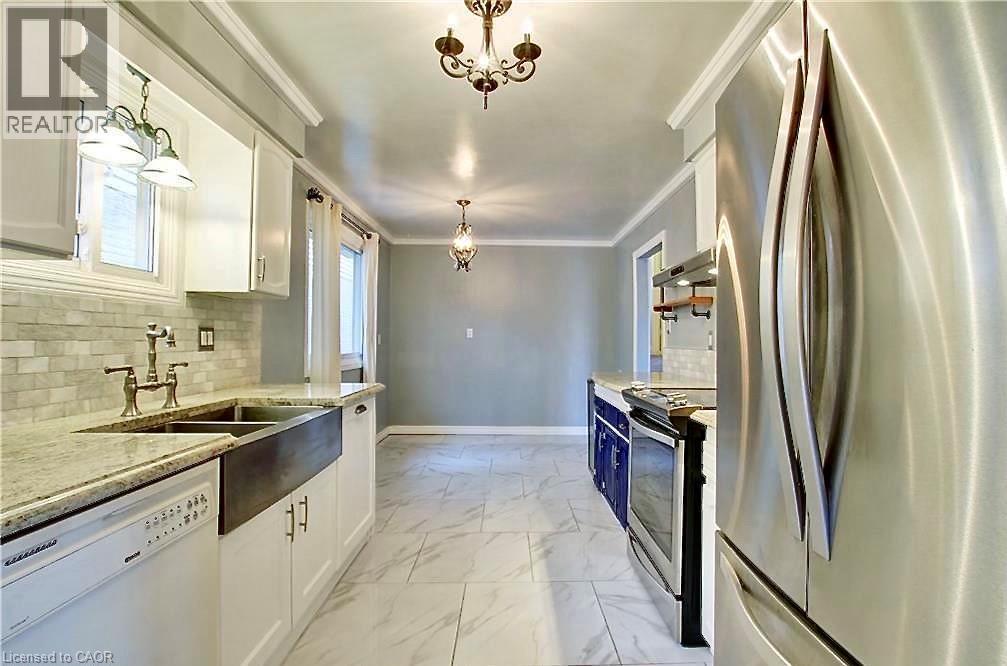 Contemporary kitchen featuring an apron front sink, granite countertops, white cabinetry, a subway tile backsplash, and stainless steel appliances - 599 Upper Horning Road Unit# Main/Upper, Hamilton, ON