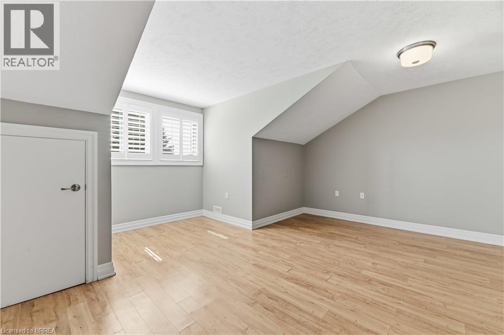 Room with wood-finish flooring, a sloped ceiling, and a flush-mount ceiling light fixture - 29 Archdeacon Clark Trail, Hamilton, ON