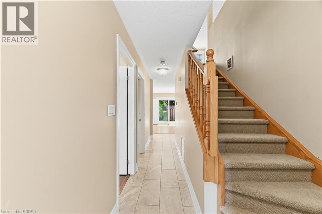 Entryway featuring a carpeted staircase with wood banister and balusters - 29 Archdeacon Clark Trail, Hamilton, ON
