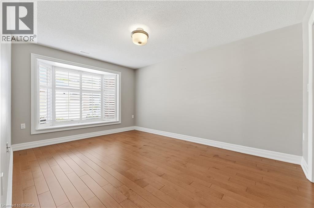 Room featuring a bay window with plantation shutters, wood-finish flooring, and a semi-flush mount ceiling light fixture - 29 Archdeacon Clark Trail, Hamilton, ON