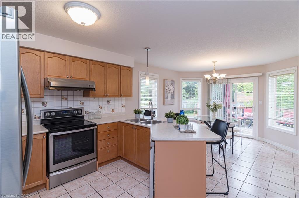 Kitchen featuring wood cabinetry, stainless steel range, and tile flooring - 566 Avignon Place, Waterloo, ON
