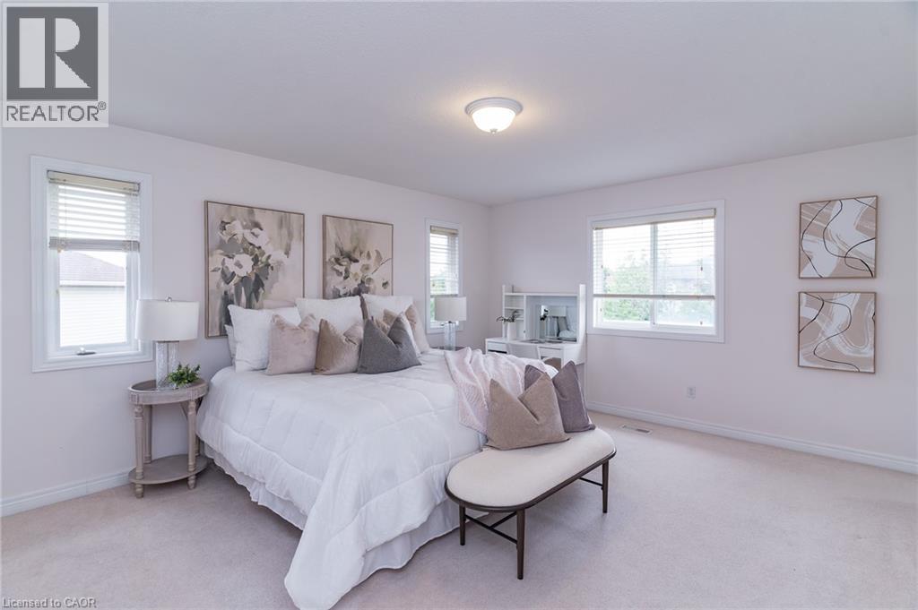 Carpeted bedroom featuring white baseboards, light wall paint, and multiple windows with blinds - 566 Avignon Place, Waterloo, ON