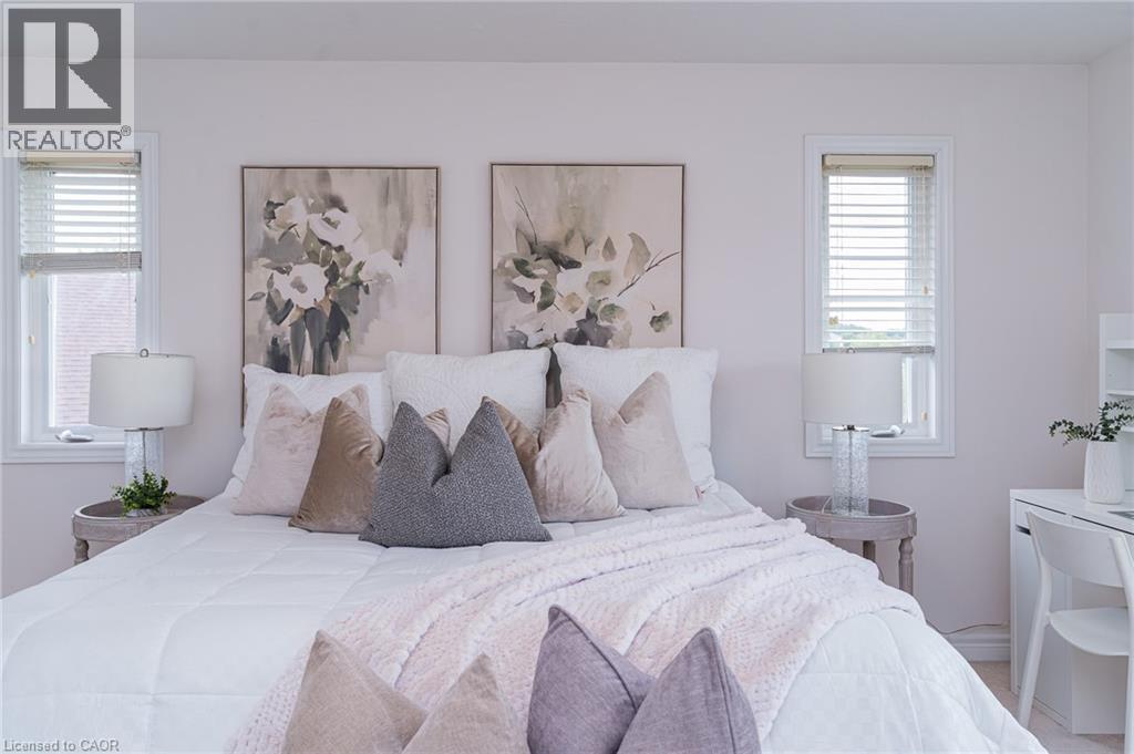 Bedroom featuring two windows with blinds, a built-in desk, and light-toned wall finishes - 566 Avignon Place, Waterloo, ON