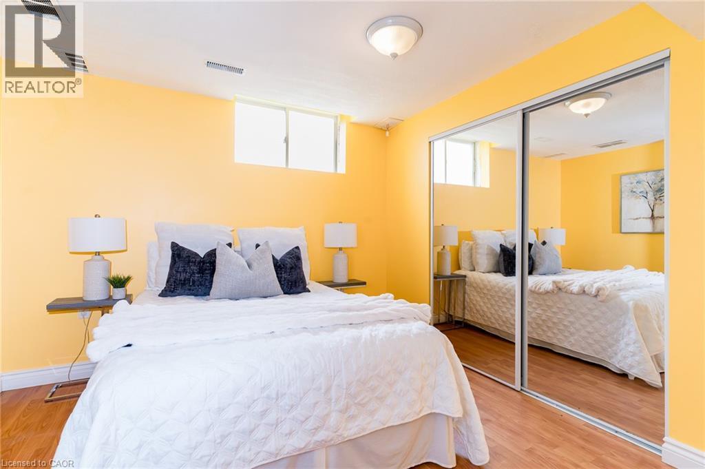 Bedroom featuring wood-finish flooring, a ceiling-mounted light fixture, and a window - 566 Avignon Place, Waterloo, ON