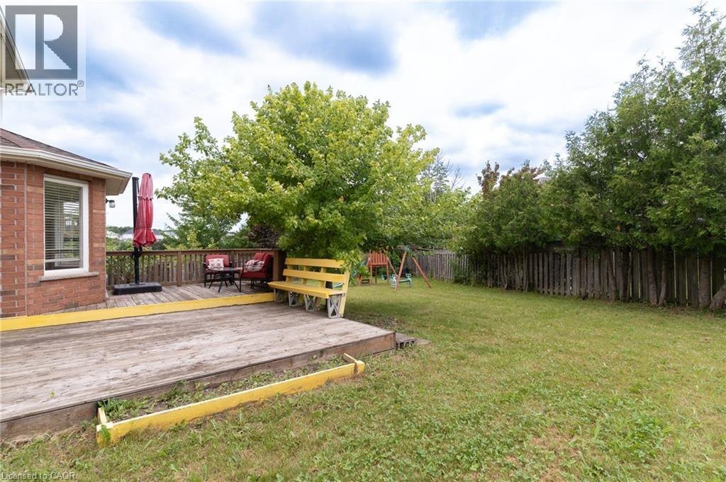 Expansive backyard featuring a multi-level wood deck, manicured lawn, and mature trees providing natural privacy - 566 Avignon Place, Waterloo, ON