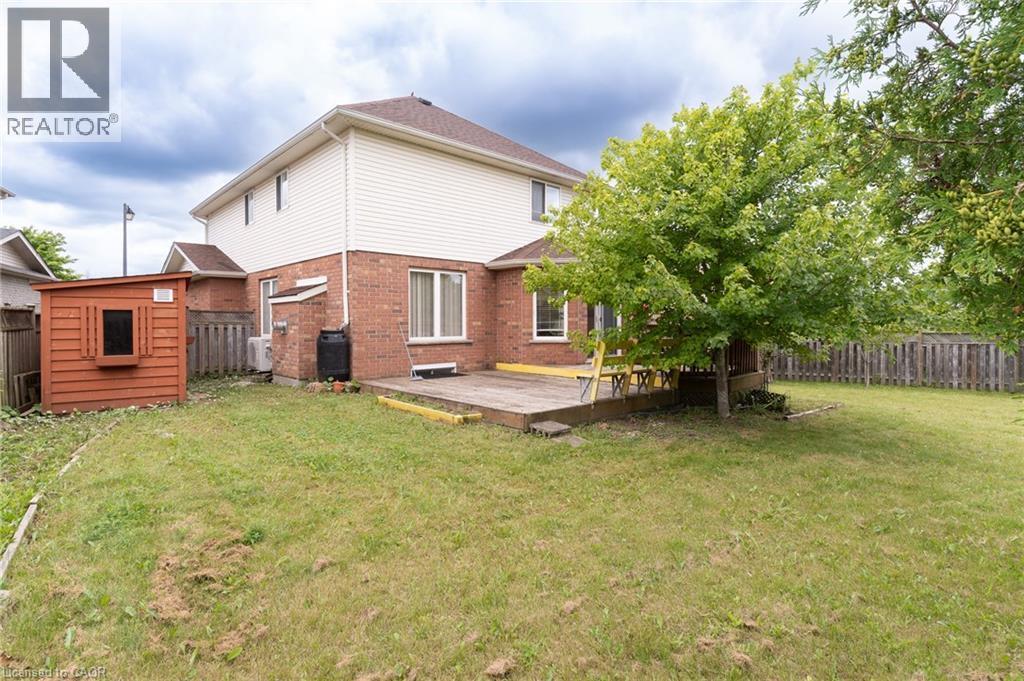 Spacious rear yard featuring a wooden deck, mature trees, and a storage shed - 566 Avignon Place, Waterloo, ON