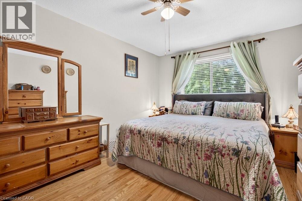 Wood-finish flooring with a ceiling fan light fixture and a window featuring horizontal blinds - 2440 Cyprus Avenue, Burlington, ON