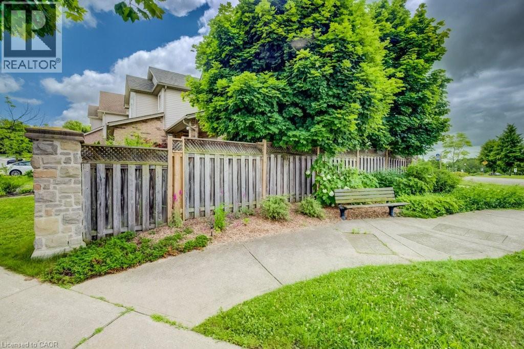 Exterior property featuring a stone pillar, a wood fence with lattice accents, mature trees, and a concrete pathway - 123 Forest Edge Trail, Kitchener, ON