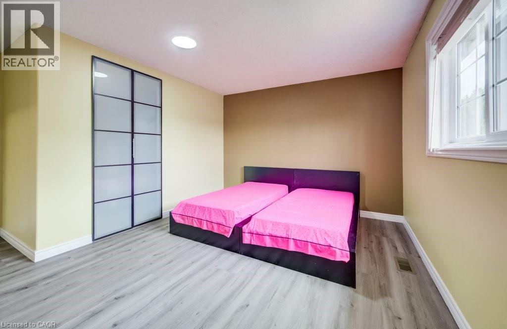 Bedroom featuring wood-finish flooring, a contemporary window, and a built-in closet with frosted glass panel doors - 123 Forest Edge Trail, Kitchener, ON