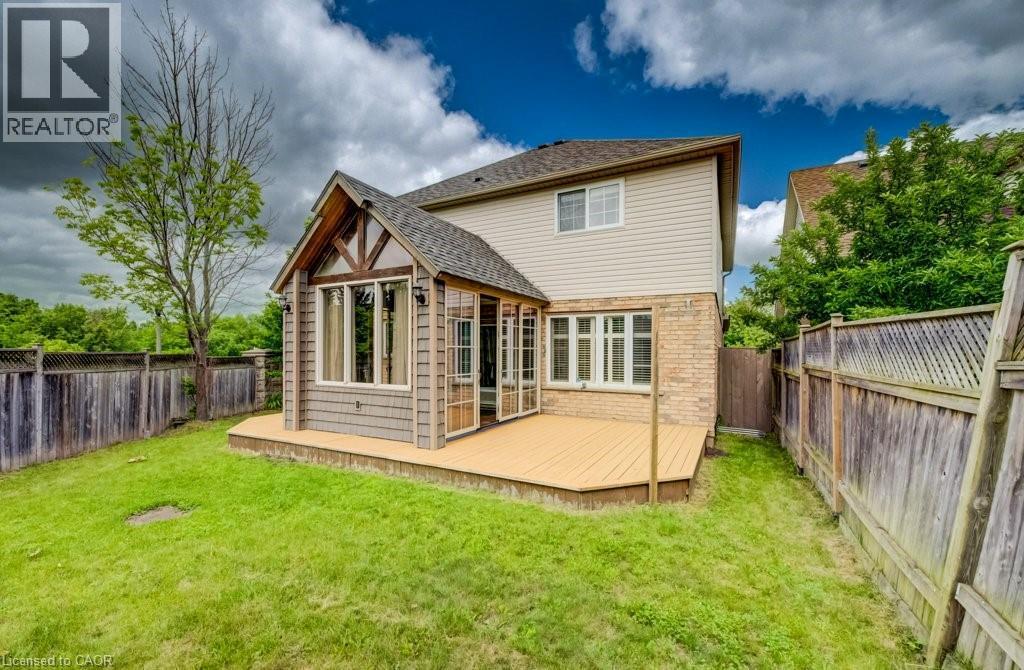 Expansive backyard featuring a large wooden deck, a sunroom extension with multiple windows, and natural wood fencing - 123 Forest Edge Trail, Kitchener, ON