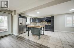 Modern kitchen featuring dark cabinetry, stainless steel appliances, and a mosaic tile backsplash -