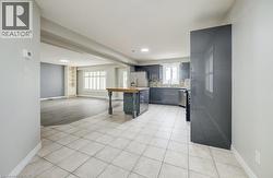 Open-concept kitchen and living area featuring tile flooring, a central island with wood-finish countertop, dark cabinetry, and stainless steel appliances -