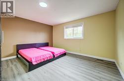 Room featuring wood-finish flooring, a window with white trim, a flush-mount ceiling light, and neutral-toned painted walls -