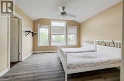 Room featuring wood-finish flooring, a vaulted ceiling, and three large windows -