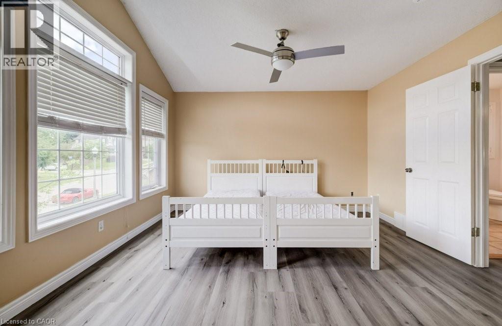 Room featuring vaulted ceilings, wood-finish flooring, multiple windows with blinds, a ceiling fan, and a six-panel interior door - 123 Forest Edge Trail, Kitchener, ON - Indoor Photo Showing Bedroom