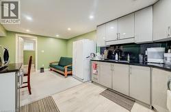 Compact kitchen area featuring light-toned cabinetry, dark countertops, and a full-size refrigerator -