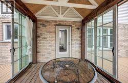 Covered outdoor patio with wood-finish flooring and exposed beam ceiling -