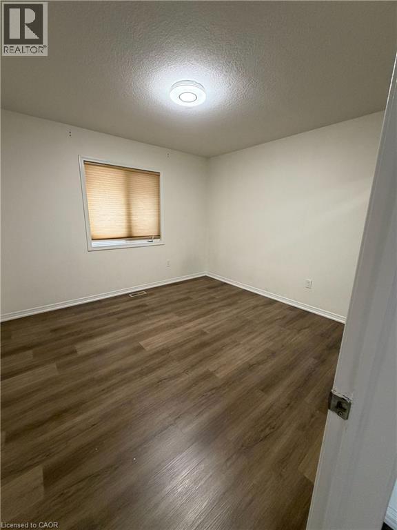 Room featuring wood-finish flooring, a window with horizontal blinds, and a flush-mount ceiling light fixture - 235 Apple Hill Crescent, Kitchener, ON