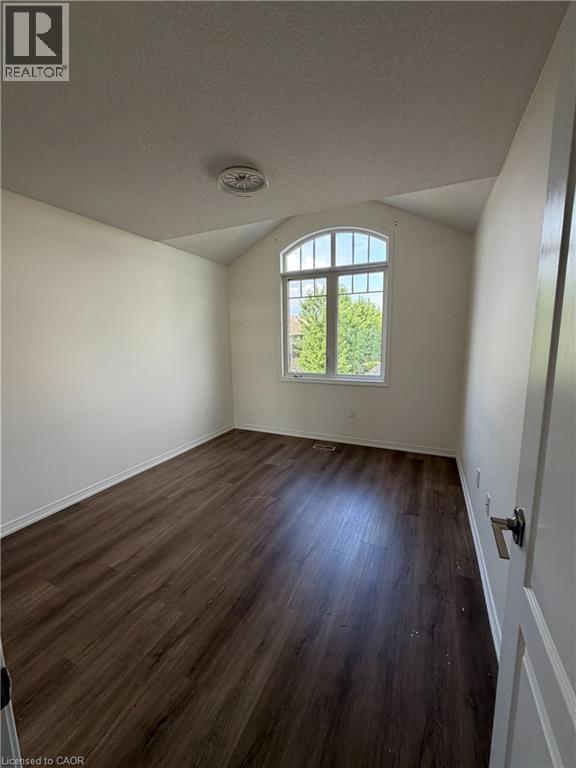 Room featuring a prominent arched window, wood-finish flooring, white baseboards, and a neutral color palette - 235 Apple Hill Crescent, Kitchener, ON