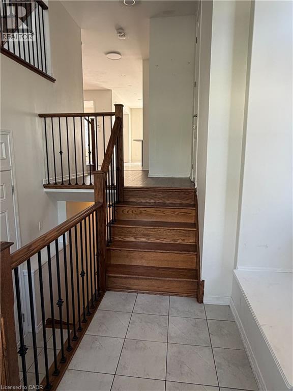 Grand entry featuring a light tile floor, natural wood staircase with wrought iron balusters, and a built-in bench - 235 Apple Hill Crescent, Kitchener, ON