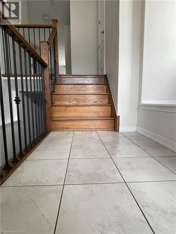 Foyer featuring large format floor tiles, hardwood stairs, and wrought iron balusters with wood handrails - 235 Apple Hill Crescent, Kitchener, ON