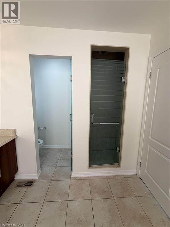 Bathroom featuring tile flooring, a dark wood-finish vanity with a light countertop, a separate water closet, and a frosted glass shower enclosure - 235 Apple Hill Crescent, Kitchener, ON