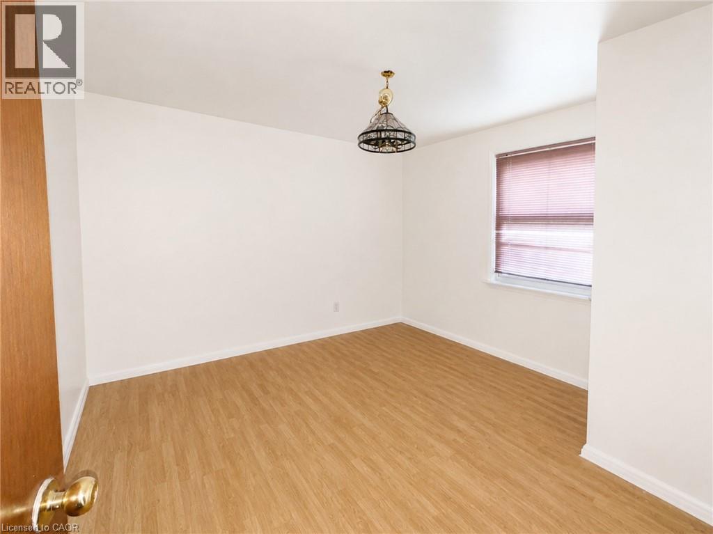 Main Floor Bedroom featuring wood-finish flooring, white walls, and a window with blinds - 83 East 41St Street, Hamilton, ON - Indoor Photo Showing Other Room
