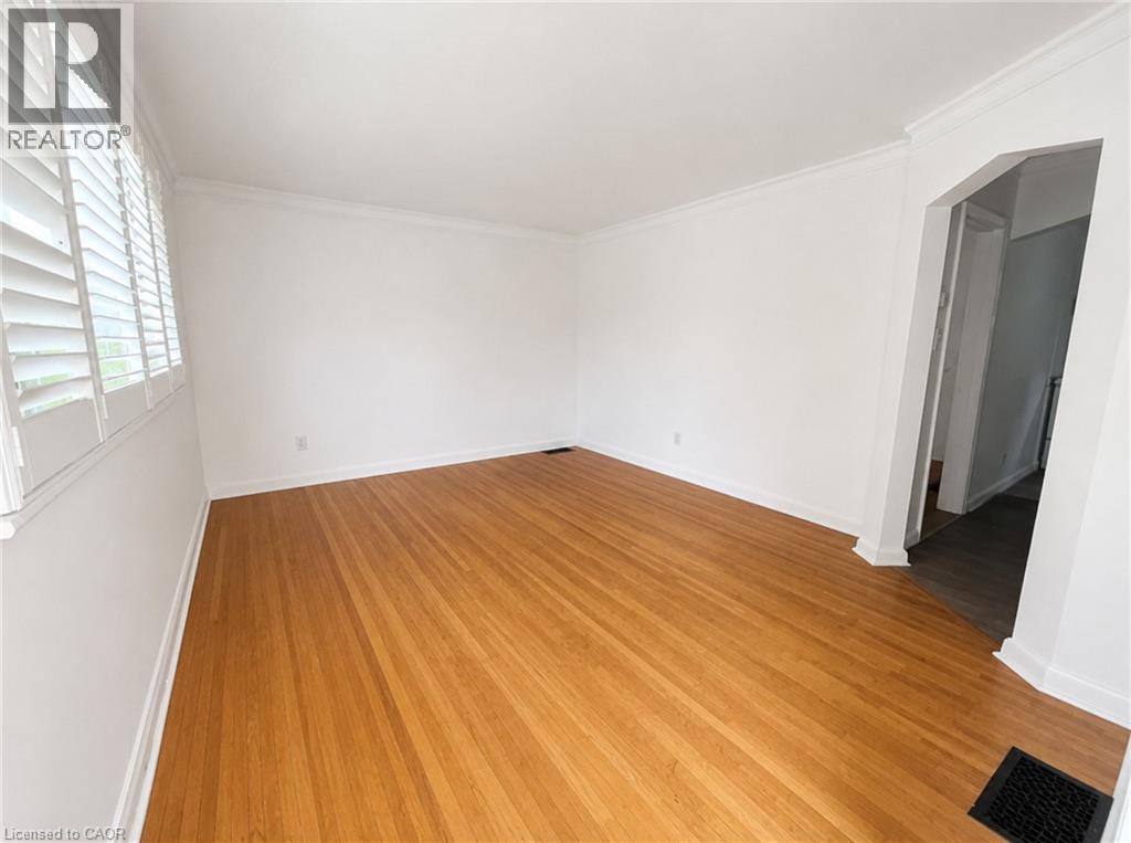 Spacious room featuring wood-finish flooring and white walls - 83 East 41St Street, Hamilton, ON - Indoor Photo Showing Other Room
