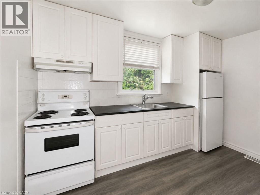 Kitchen featuring white cabinetry, dark countertops, a white electric range, and a white refrigerator - 83 East 41St Street, Hamilton, ON - Indoor Photo Showing Kitchen