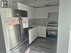 Kitchen featuring white shaker cabinetry, stainless steel appliances, a white marble-look backsplash, white countertops, and wood-finish flooring -