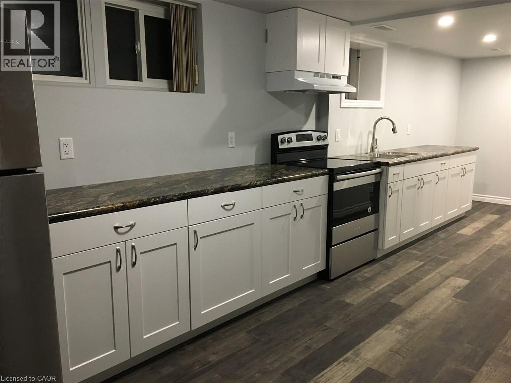Kitchen featuring white shaker-style cabinetry, dark speckled countertops, and wood-finish flooring - 92 Pattandon Avenue Unit# C, Kitchener, ON - Indoor Photo Showing Kitchen