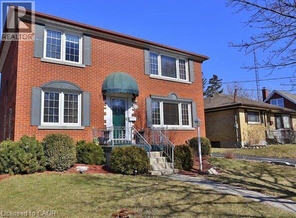 Brick exterior with white-framed windows, decorative shutters, and a green fabric awning over the entry - 92 Pattandon Avenue Unit# C, Kitchener, ON - Outdoor