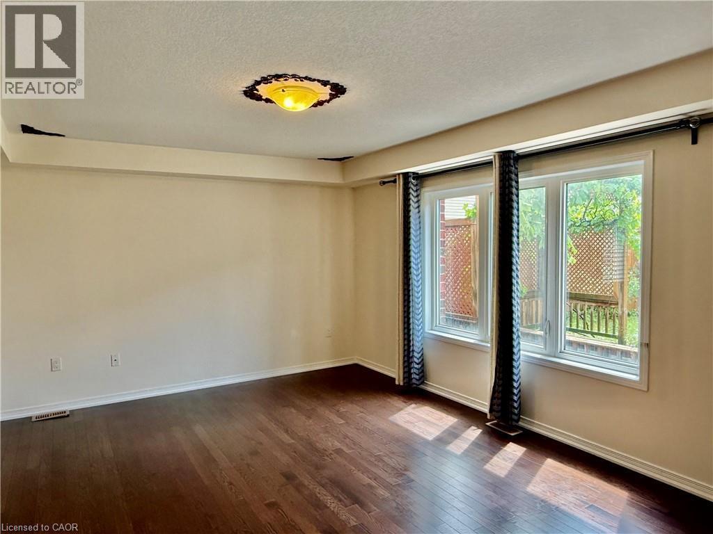 Spacious interior featuring wood-finish flooring, light-colored walls, and a large window unit providing ample natural light - 386 Apple Hill Crescent, Kitchener, ON