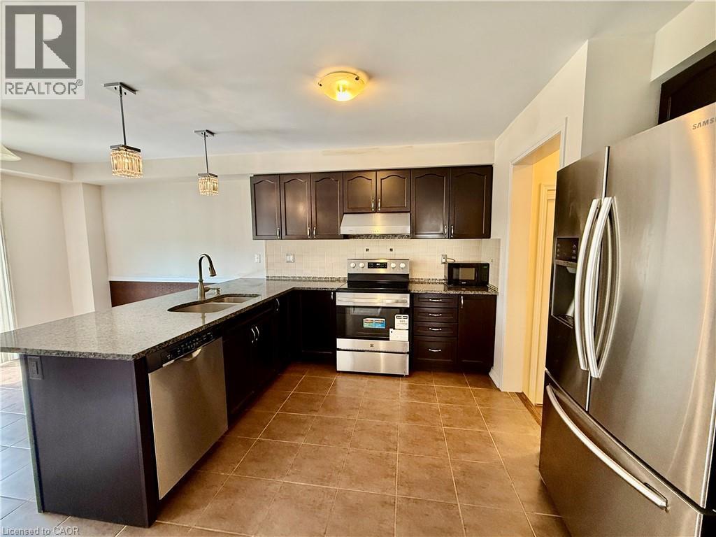 Kitchen featuring dark wood cabinetry, light-toned granite-style countertops, stainless steel appliances, and a tiled floor - 386 Apple Hill Crescent, Kitchener, ON