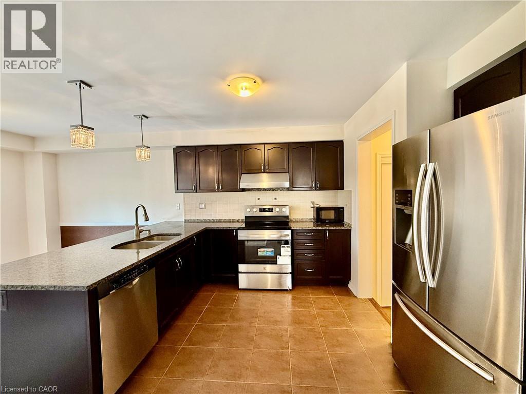 Contemporary kitchen featuring dark wood cabinetry, stainless steel appliances, granite countertops, and tile flooring - 386 Apple Hill Crescent, Kitchener, ON