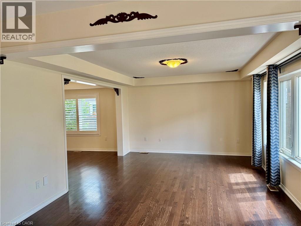 Spacious room featuring rich wood-finish flooring, an ornate ceiling light fixture, and a decorative ceiling medallion - 386 Apple Hill Crescent, Kitchener, ON