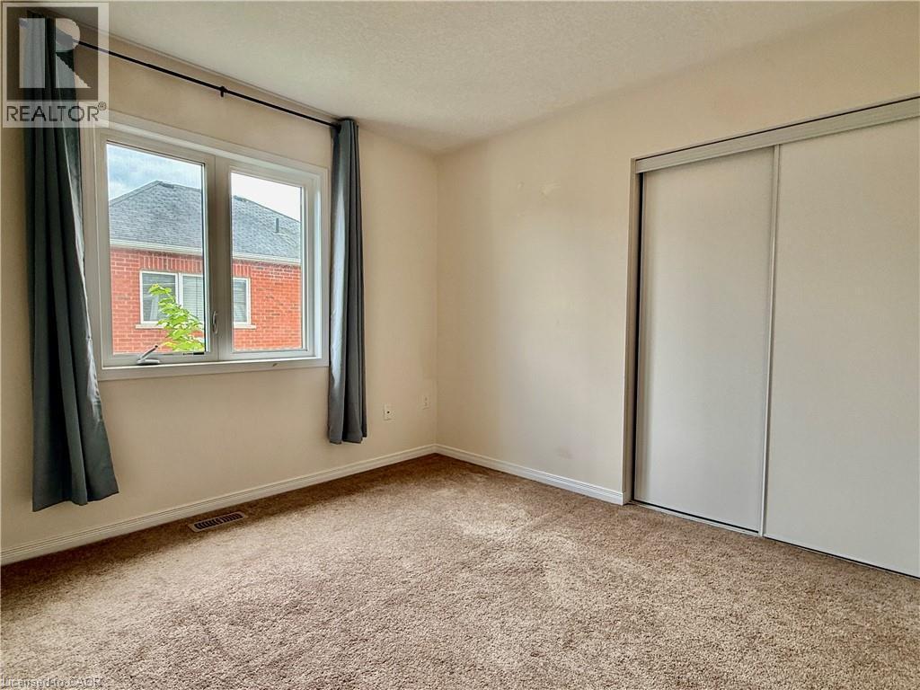 Carpeted room featuring a double window, baseboard trim, and a sliding door closet - 386 Apple Hill Crescent, Kitchener, ON