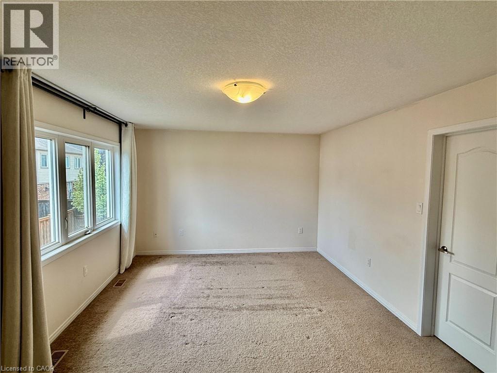 Expansive room featuring neutral wall paint, a multi-pane window with white trim, and a flush-mount ceiling light fixture - 386 Apple Hill Crescent, Kitchener, ON