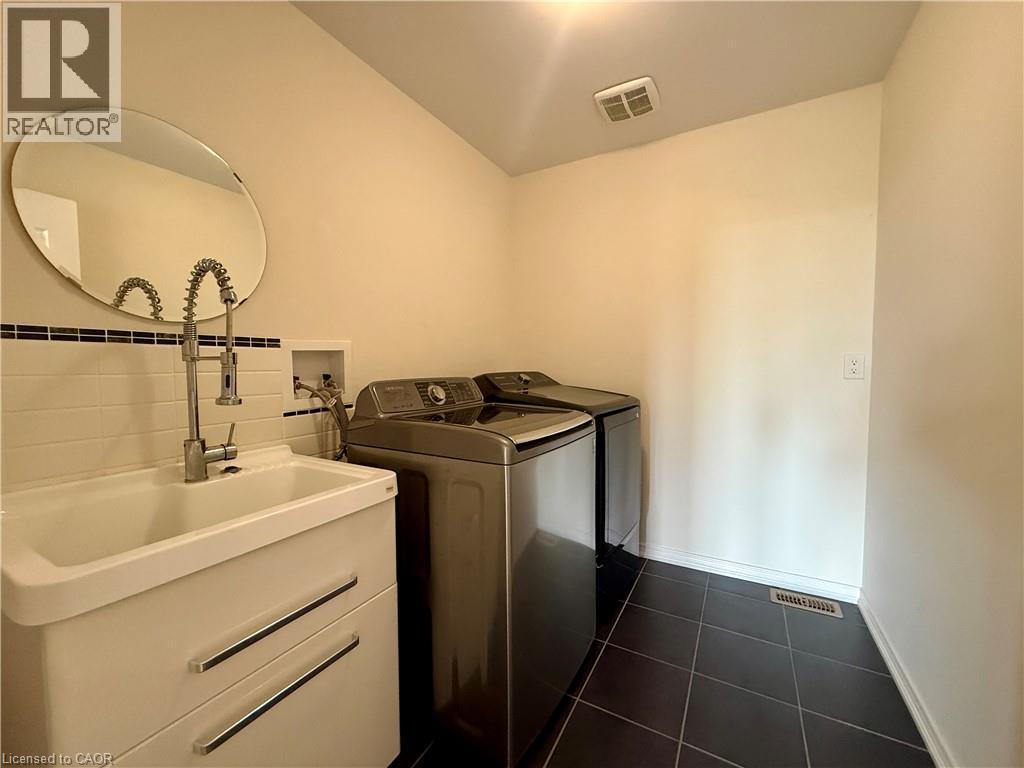 Laundry area with dark tiled flooring and light-toned walls - 386 Apple Hill Crescent, Kitchener, ON