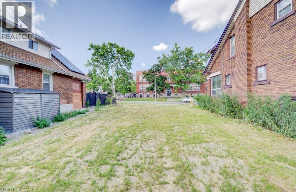 Expansive grassy lot with surrounding brick and siding structures - 153 Courtland Avenue E, Kitchener, ON