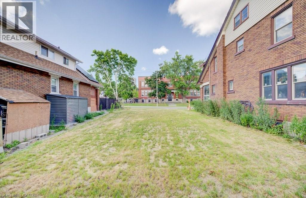 Expansive grassy yard area with brick exterior structures bordering each side - 153 Courtland Avenue E, Kitchener, ON