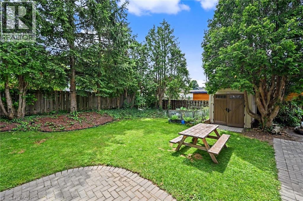 Expansive backyard featuring a lush lawn, mature trees, and a paved patio area - 56 Everton Place, Hamilton, ON