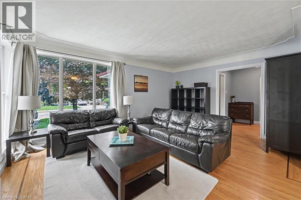 Spacious living area featuring large picture windows, wood-finish flooring, light blue wall paint, and a classic white ceiling - 56 Everton Place, Hamilton, ON