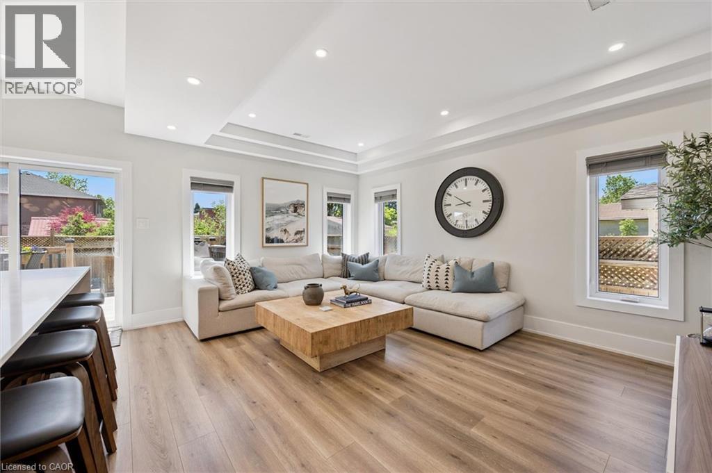 Open-concept living area with wood-finish flooring, recessed lighting, and a tray ceiling - 63 Plymouth Road, Kitchener, ON